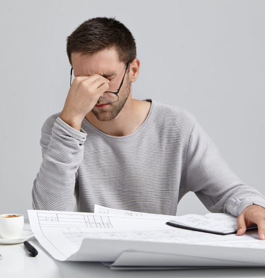 Overworked professional young male worker, has tired expression, takes off glasses as has eye pain, work all night at construction or business project, want to have sleep, tries to finish work quickly